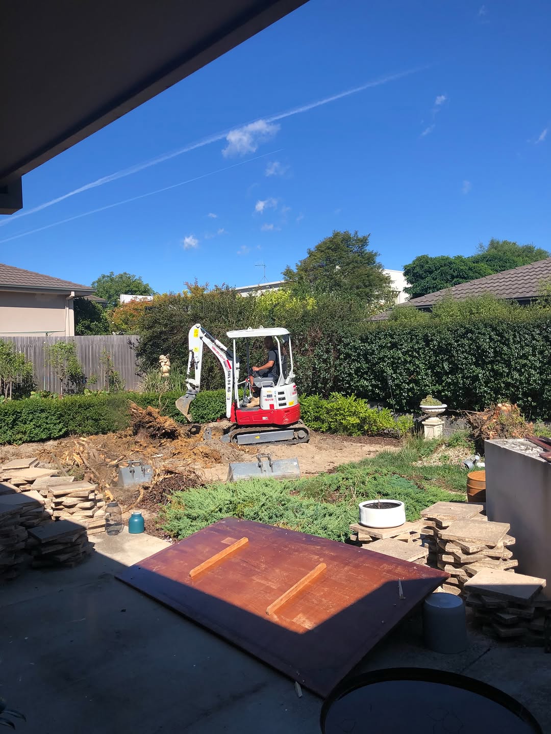 Excavator clearing a backyard at the start of a landscaping job
